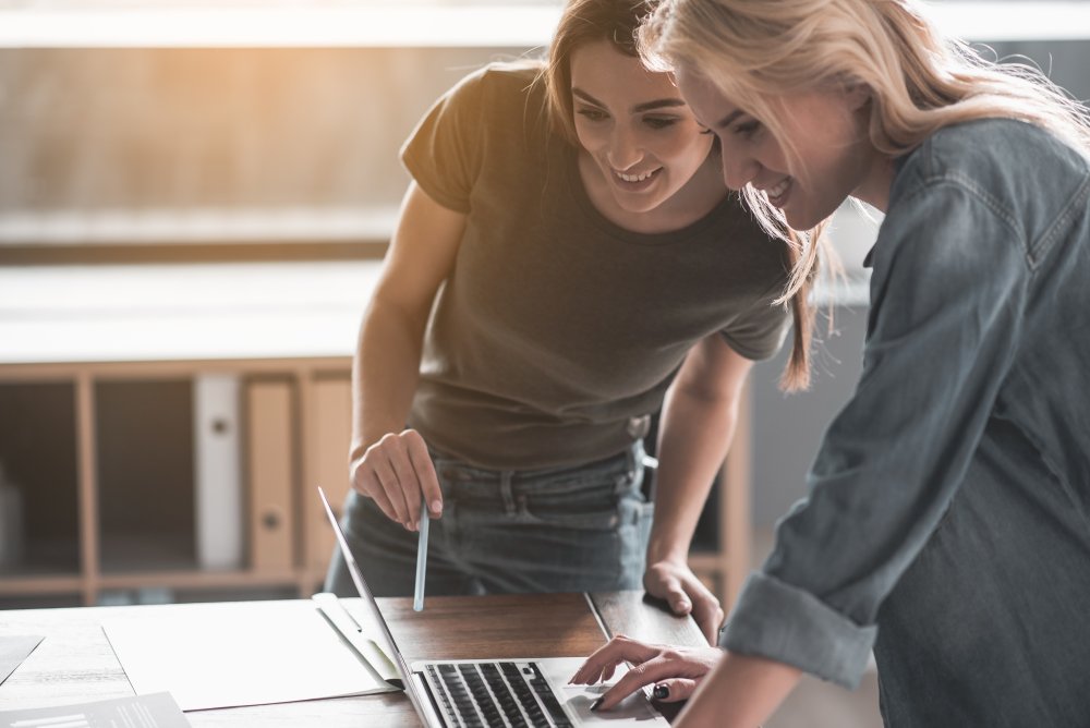 Two women in office pointing at a screen