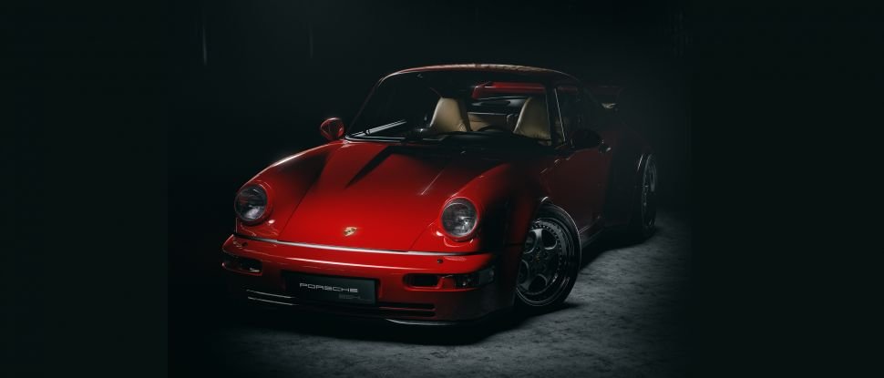 A red topless sports car sits in dramatic shadow