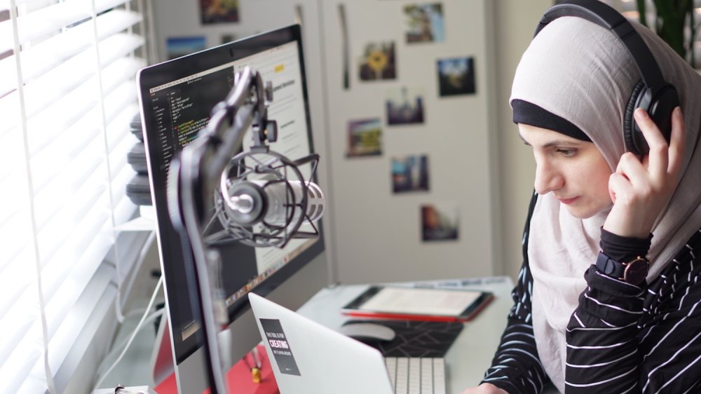 Generate speaker Sara Soueidan sits at her desk wearing headphones and looking deep in concentration.