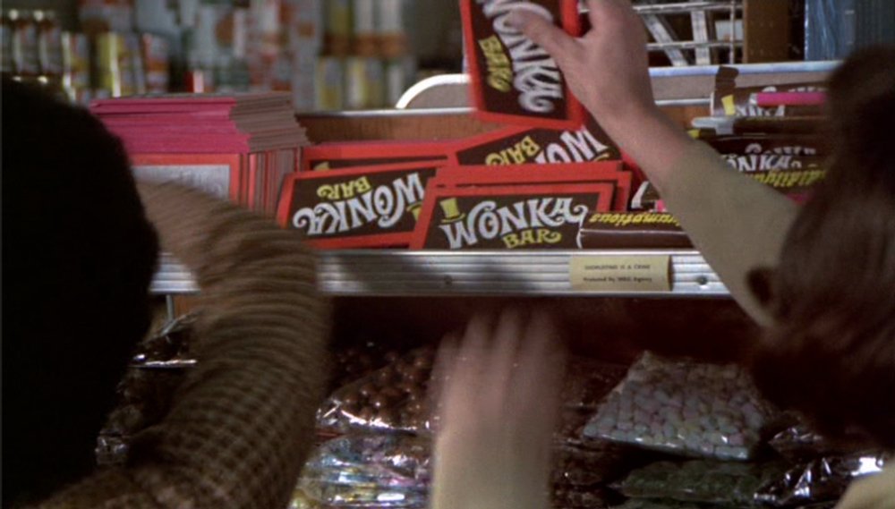 Children's hands grabbing Wonka bars from a shelf