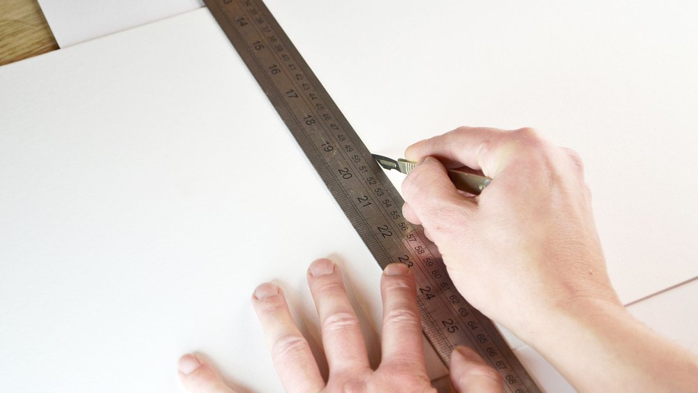 someone measuring a piece of board with a ruler