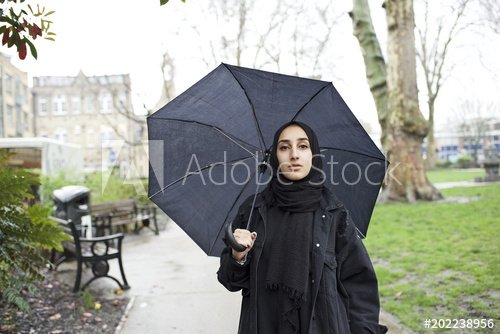 Muslim woman holding umbrella in London park