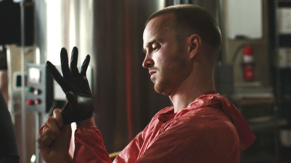 Young man wearing orange overalls puts on glove