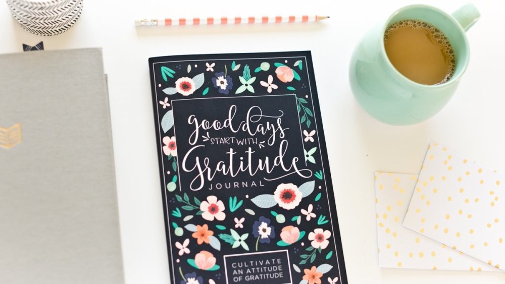 Book on desk with assorted stationery and coffee cup