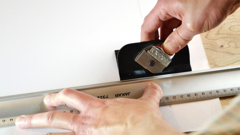 A person cutting a mount board with a cutter