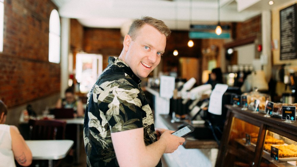 Front-end developer using his phone in a cafe.