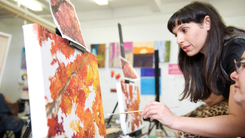 Woman teaching another woman to paint