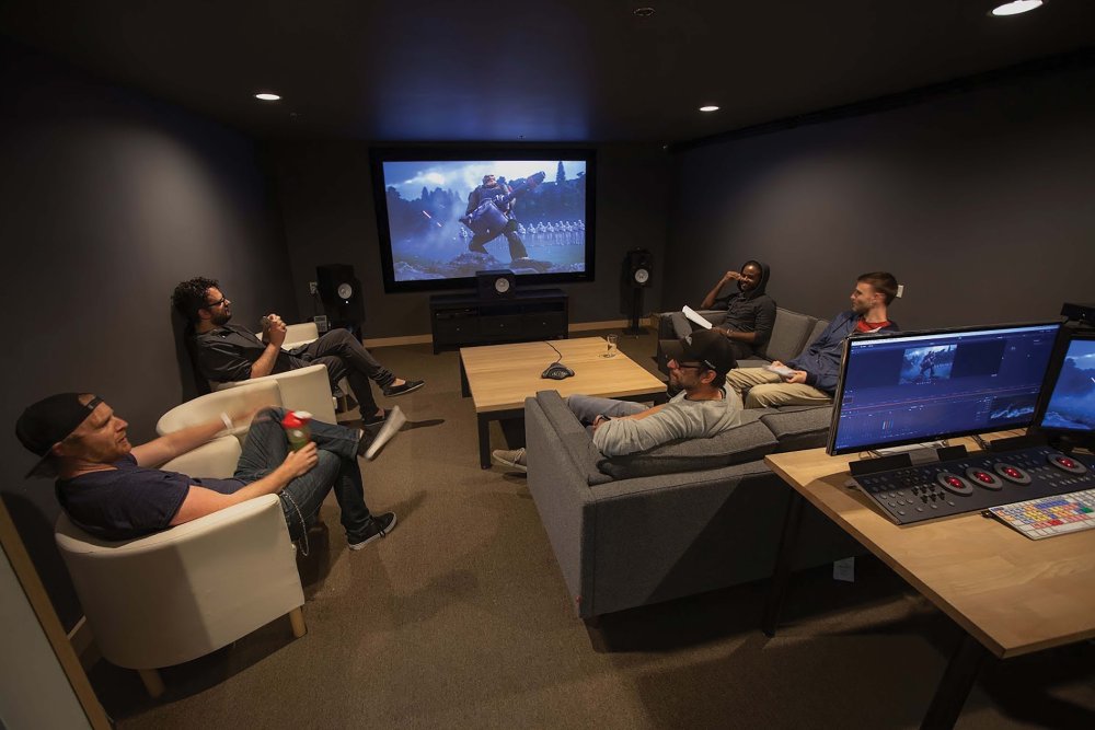 People sitting in a dim room in front of a video screen