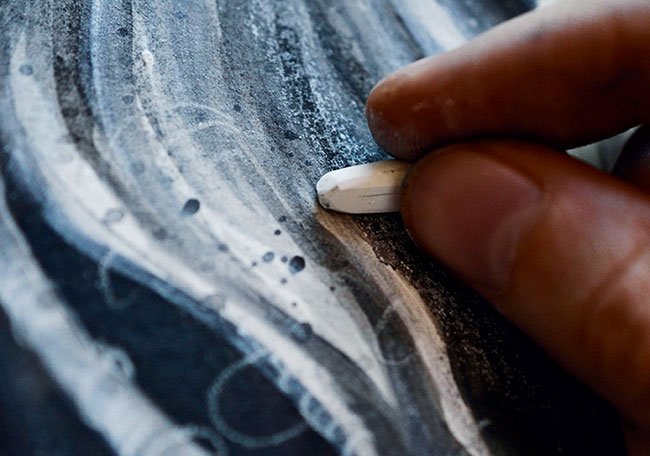 Close up of a hand adding white charcoal highlights to the hair