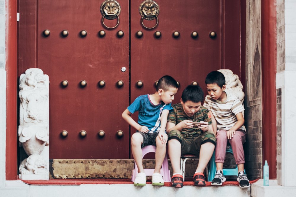 Three young boys gathered around a handheld device