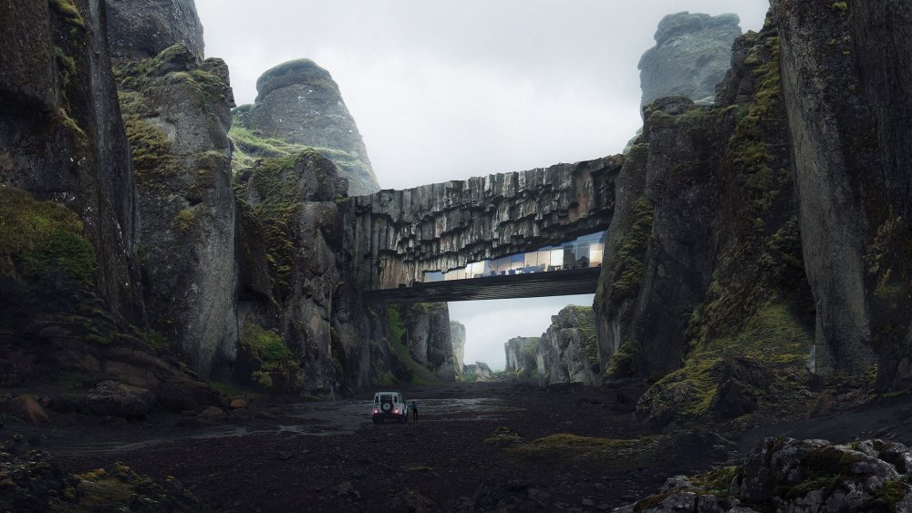 Jeep driving towards an overhead bridge in a mountainous ravine