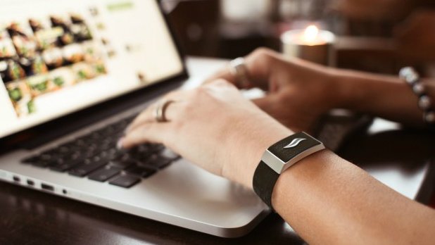 Person typing, wearing a smart bracelet