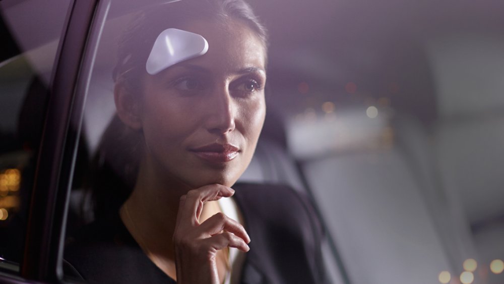 Woman wearing a triangular plastic Thync on her forehead