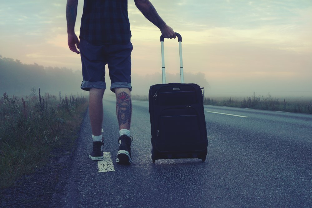 Man walking along deserted road with suitcase