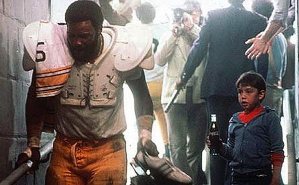 A boy offers a Coke to an injured football player