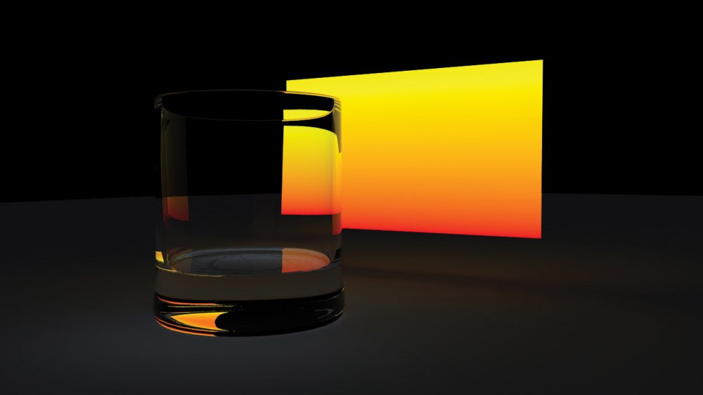 A glass tumbler in front of an illuminated screen