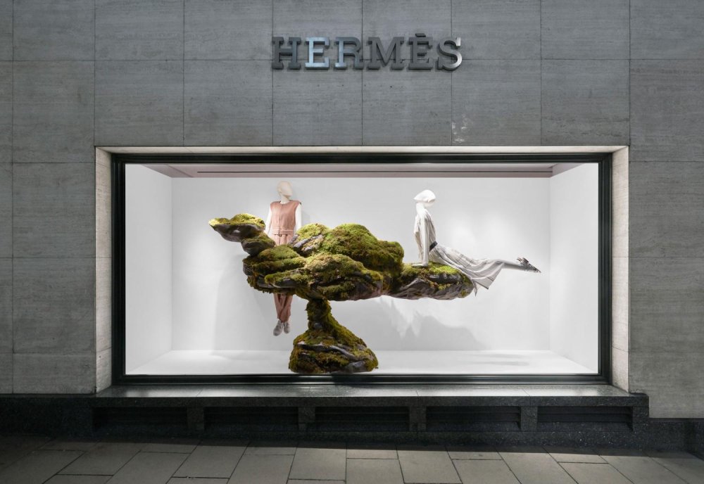 Hermes shop window with mannequins balanced on mossy rocks