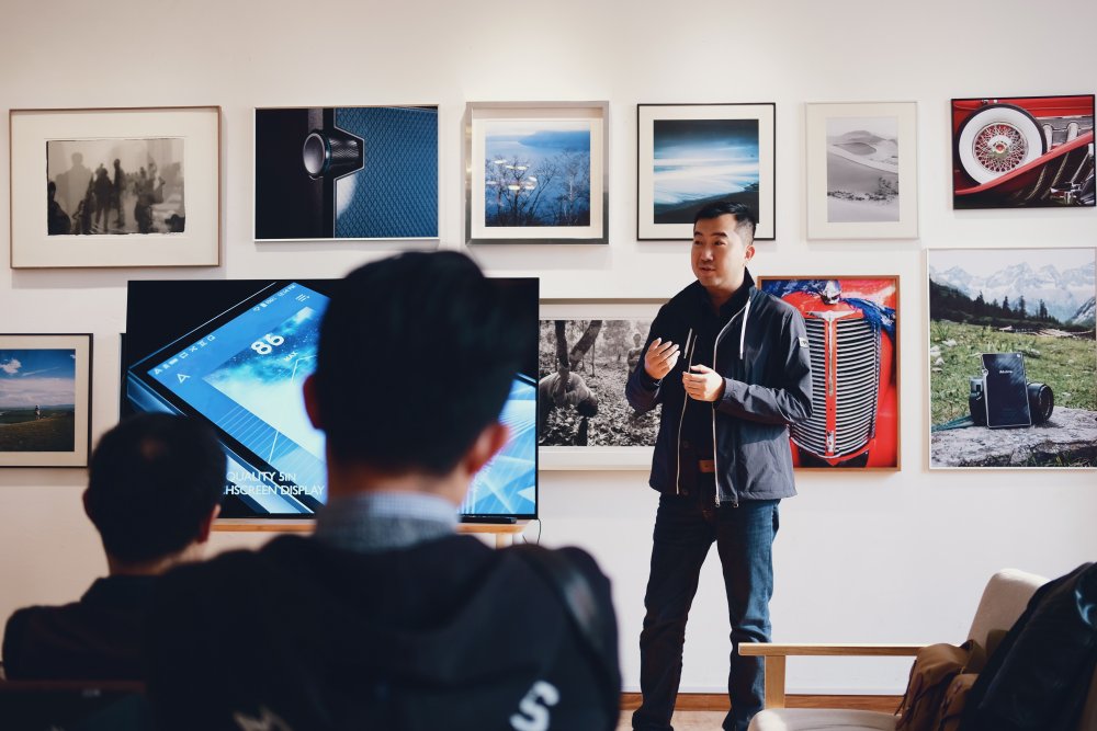 Man talking to audience in front of framed art photography